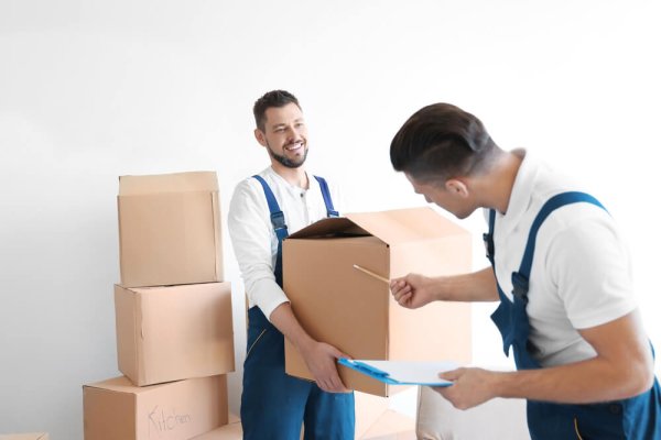 Delivery men with moving boxes in room at new home