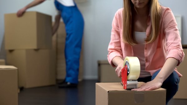 Lady packing things in box, moving company worker carrying baggage, services