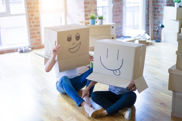 Couple wearing funny cardboard boxes with happy faces, moving to