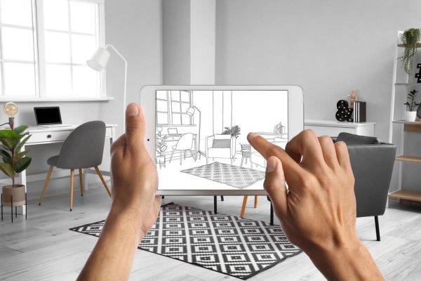 Male designer holding tablet computer with drawing of new living room interior